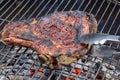 Grilled beef rib on a barbecue grill caught with special pliers Royalty Free Stock Photo