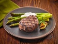 Grilled beef steak and asparagus on dark plate