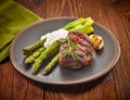 Grilled beef steak and asparagus on dark plate