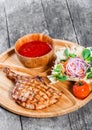 Grilled beef steak on bone, fresh salad, grilled vegetables and tomato sauce on cutting board on wooden background Royalty Free Stock Photo