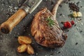 Grilled beef tomahawk steak fillet with ingredients and herbs on black board, product image for restaurant