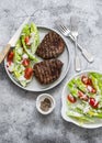 Grilled beef steak and fresh romaine salad cherry tomatoes yogurt dressing salad on a grey background, top view