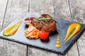 Grilled beef steak with fresh salad and bbq sauce on stone slate background on wooden background close up. Royalty Free Stock Photo