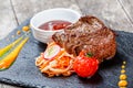 Grilled beef steak with fresh salad and bbq sauce on stone slate background on wooden background close up. Royalty Free Stock Photo