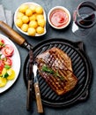 Grilled beef steak on grill pan served with tomato salad, potatoes balls and wine. Barbecue, bbq meat beef tenderloin Royalty Free Stock Photo