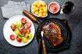 Grilled beef steak on grill pan served with tomato salad, potatoes balls and wine. Barbecue, bbq meat beef tenderloin Royalty Free Stock Photo