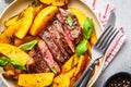 Grilled beef steak with potatoes and basil in a white plate, top view Royalty Free Stock Photo