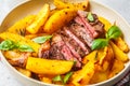 Grilled beef steak with potatoes and basil in a white plate on white background Royalty Free Stock Photo