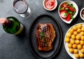 Grilled beef steak served on cast iron plate with tomato salad, potatoes balls and red wine. Barbecue, bbq meat beef Royalty Free Stock Photo