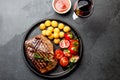 Grilled beef steak served on cast iron plate with tomato salad, potatoes balls and red wine. Barbecue, bbq meat beef Royalty Free Stock Photo