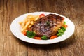 Grilled beef steak served with French fries and vegetables on a white plate Royalty Free Stock Photo