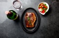 Grilled beef steak served on wooden table with tomato salad and red wine. Barbecue, bbq meat beef tenderloin. Top view Royalty Free Stock Photo