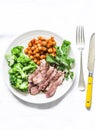 Grilled beef steak, spicy stewed chickpeas, broccoli - delicious healthy lunch on a light background, top view