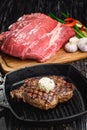 Grilled Black Angus Steak on grill iron pan on wooden black background with raw Royalty Free Stock Photo