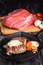 Grilled Black Angus Steak on grill iron pan on wooden black background with raw Royalty Free Stock Photo