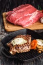 Grilled Black Angus Steak on grill iron pan on wooden black background with raw Royalty Free Stock Photo