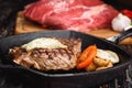 Grilled Black Angus Steak on grill iron pan on wooden black background with raw Royalty Free Stock Photo