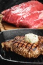 Grilled Black Angus Steak on grill iron pan on wooden black background with raw Royalty Free Stock Photo