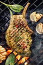 Grilled bone-in pork chop, pork steak, tomahawk in a herb marinade on a flaming grill, close-up, top view.