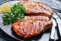 Grilled bone-in pork chops on a black plate