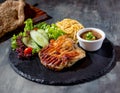 Grilled Boneless Chicken Steak with chili sauce, salad, noodles in dish side view on dark background