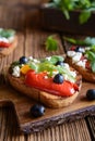 Grilled bread slices topped with baked red, green and yellow bell pepper, black olives, arugula and Feta cheese Royalty Free Stock Photo