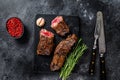 Grilled brisket steaks in bbq sauce on a marble board. Black background. Top view Royalty Free Stock Photo