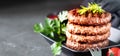 Grilled burger patties with herbs, spices on a dark background, copy space
