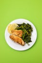 Grilled caviar cod fish with greens and fresh lemon on white small plate. Royalty Free Stock Photo