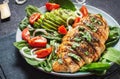 Grilled chicken breast and avocado salad with spinach and cherry tomatoes on black stone background. Healthy food, ketogenic diet