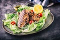 Grilled chicken breast in different variations with lettuce salad cherry tomatoes mushrooms herbs cut lemon on a wooden board or