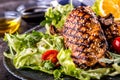 Grilled chicken breast in different variations with lettuce salad cherry tomatoes mushrooms herbs cut lemon on a wooden board or Royalty Free Stock Photo