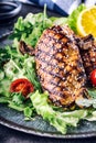 Grilled chicken breast in different variations with lettuce salad cherry tomatoes mushrooms herbs cut lemon on a wooden board or Royalty Free Stock Photo