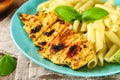 Grilled chicken breast and Penne pasta with spices and Basil. A delicious dinner in the rustic style. Selective focus Royalty Free Stock Photo