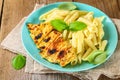 Grilled chicken breast and Penne pasta with spices and Basil. A delicious dinner in the rustic style. Selective focus Royalty Free Stock Photo