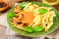 Grilled chicken breast and Penne pasta with spices and Basil. A delicious dinner in the rustic style. Selective focus Royalty Free Stock Photo