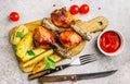 Grilled chicken drumstick bbq with potato slices on a cutting board on a stone gray background Royalty Free Stock Photo
