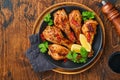 Grilled chicken drumsticks or legs or roasted bbq with spices and tomato salsa sauce on a black plate on old wooden background. To Royalty Free Stock Photo