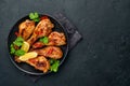 Grilled chicken drumsticks or legs or roasted bbq with spices and tomato salsa sauce on a black plate. Top view with copy space Royalty Free Stock Photo