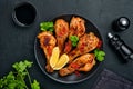 Grilled chicken drumsticks or legs or roasted bbq with spices and tomato salsa sauce on a black plate. Top view with copy space Royalty Free Stock Photo