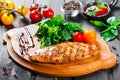 Grilled chicken fillet with fresh vegetable salad, tomatoes and sauce on wooden cutting board Royalty Free Stock Photo