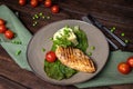 Grilled chicken fillet with mashed potatoes and green peas. Green tablecloth, dark woody background. Top view