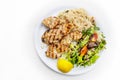 Grilled chicken fillet with mixed salad, rice and lemon, Mediterranean dish served on a plate, white table, copy space, high angle Royalty Free Stock Photo