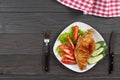 Grilled chicken fillet on white plate with tomato on dark wooden background with red cloth. With copy space. Top view Royalty Free Stock Photo