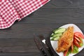 Grilled chicken fillet on white plate with tomato on dark wooden background with red cloth. With copy space. Top view Royalty Free Stock Photo