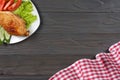 grilled chicken fillet on white plate with tomato on dark wooden background with red cloth. With copy space. Top view Royalty Free Stock Photo