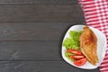 grilled chicken fillet on white plate with tomato on dark wooden background with red cloth. With copy space. Top view Royalty Free Stock Photo