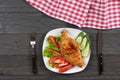 Grilled chicken fillet on white plate with tomato on dark wooden background with red cloth. With copy space. Top view Royalty Free Stock Photo