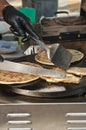 Grilled chicken and flat bread in a flat grill, being moved by a vender with knife and spatula