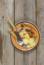 Grilled chicken leg and grilled potatoes in a plate, on a wooden table, top view Royalty Free Stock Photo